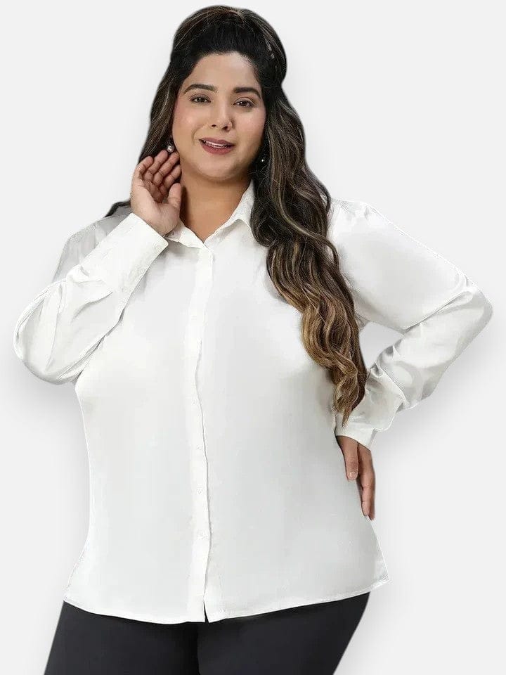 A woman with long brown hair wearing a white blouse and black pants is smiling at the camera.