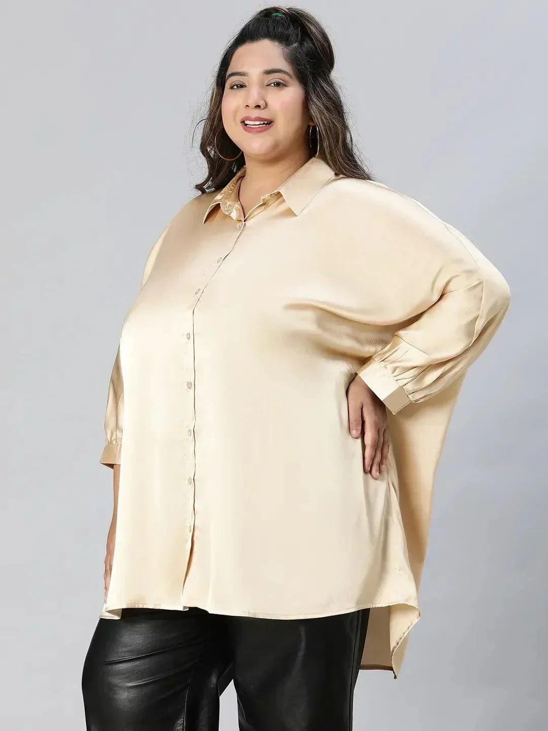 A woman with long brown hair wearing a cream-colored blouse and black pants, smiling at the camera.