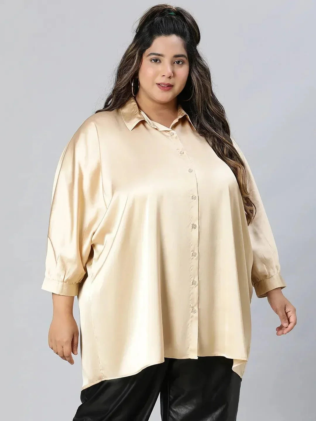 A woman with long brown hair wearing a cream-colored blouse and black pants, smiling at the camera.