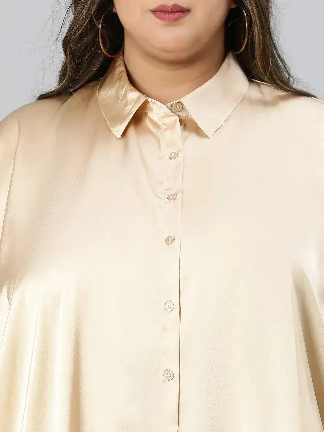 A woman with long brown hair wearing a cream-colored blouse and black pants, smiling at the camera.