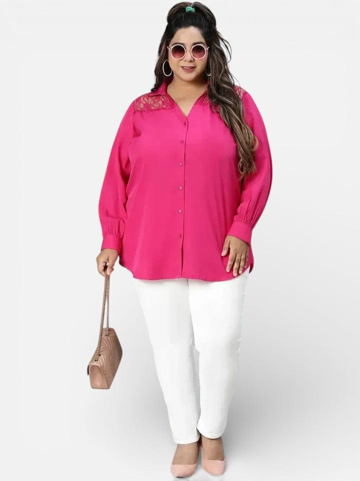 A woman wearing a bright pink blouse, white pants, and sunglasses, holding a small purse, standing against a white background.