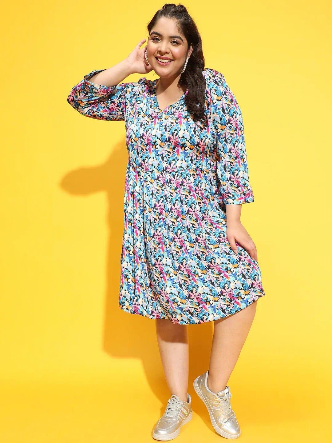 A woman wearing a colorful floral print dress and gold sneakers is smiling and posing for the camera.