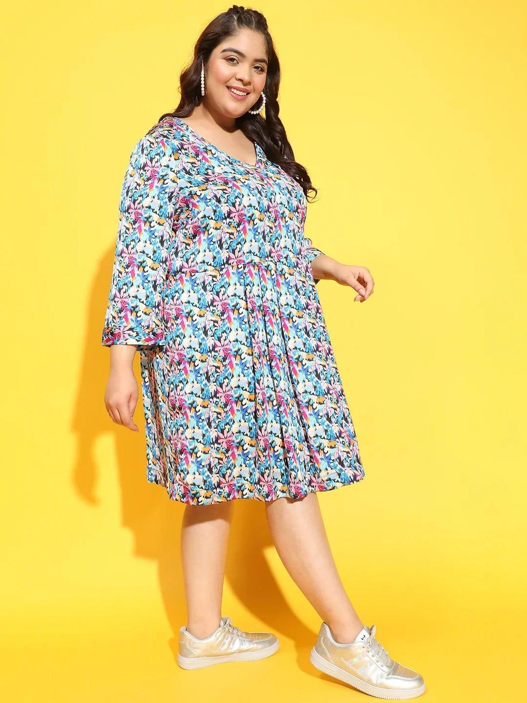A woman wearing a colorful floral print dress and gold sneakers is smiling and posing for the camera.