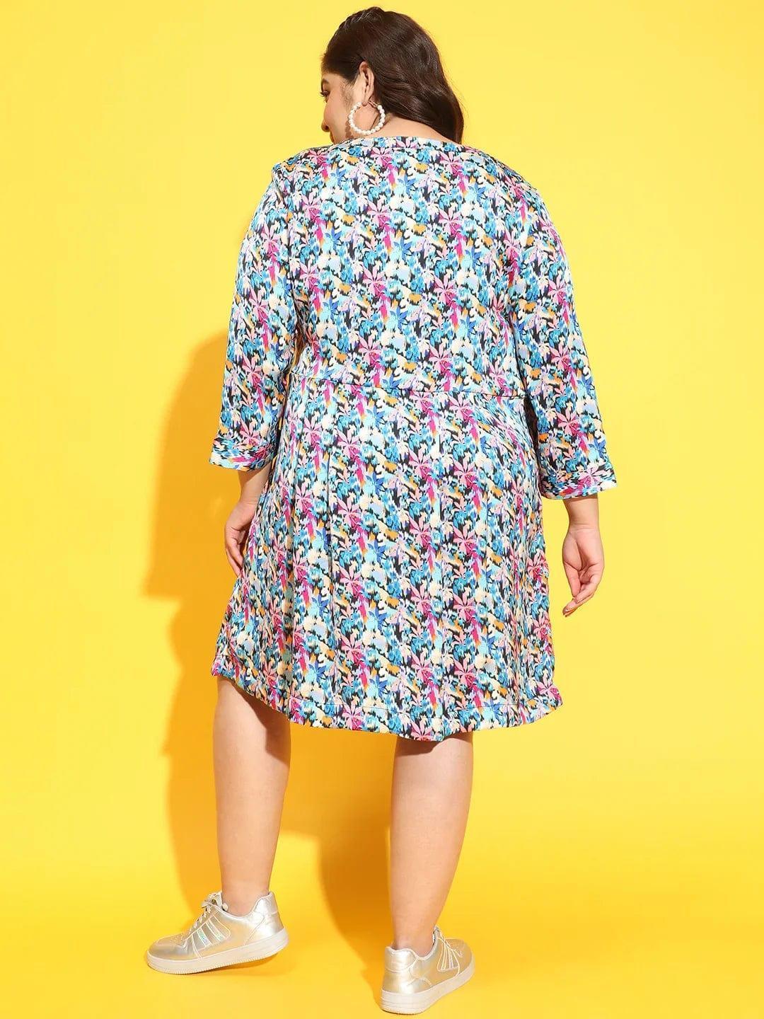 A woman wearing a colorful floral print dress and gold sneakers is smiling and posing for the camera.