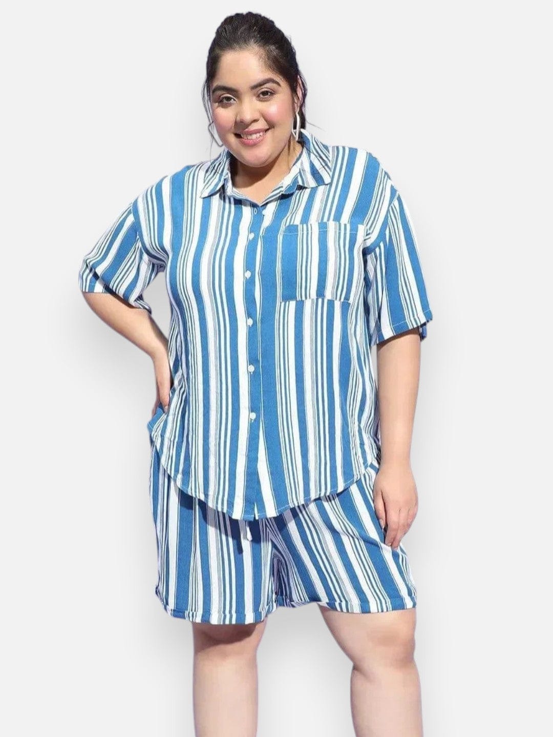 A woman wearing a blue and white striped shirt and shorts is smiling at the camera.