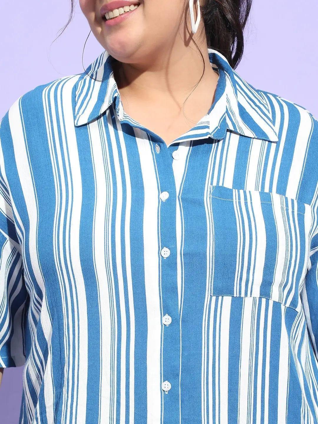A woman wearing a blue and white striped shirt and shorts is smiling at the camera.