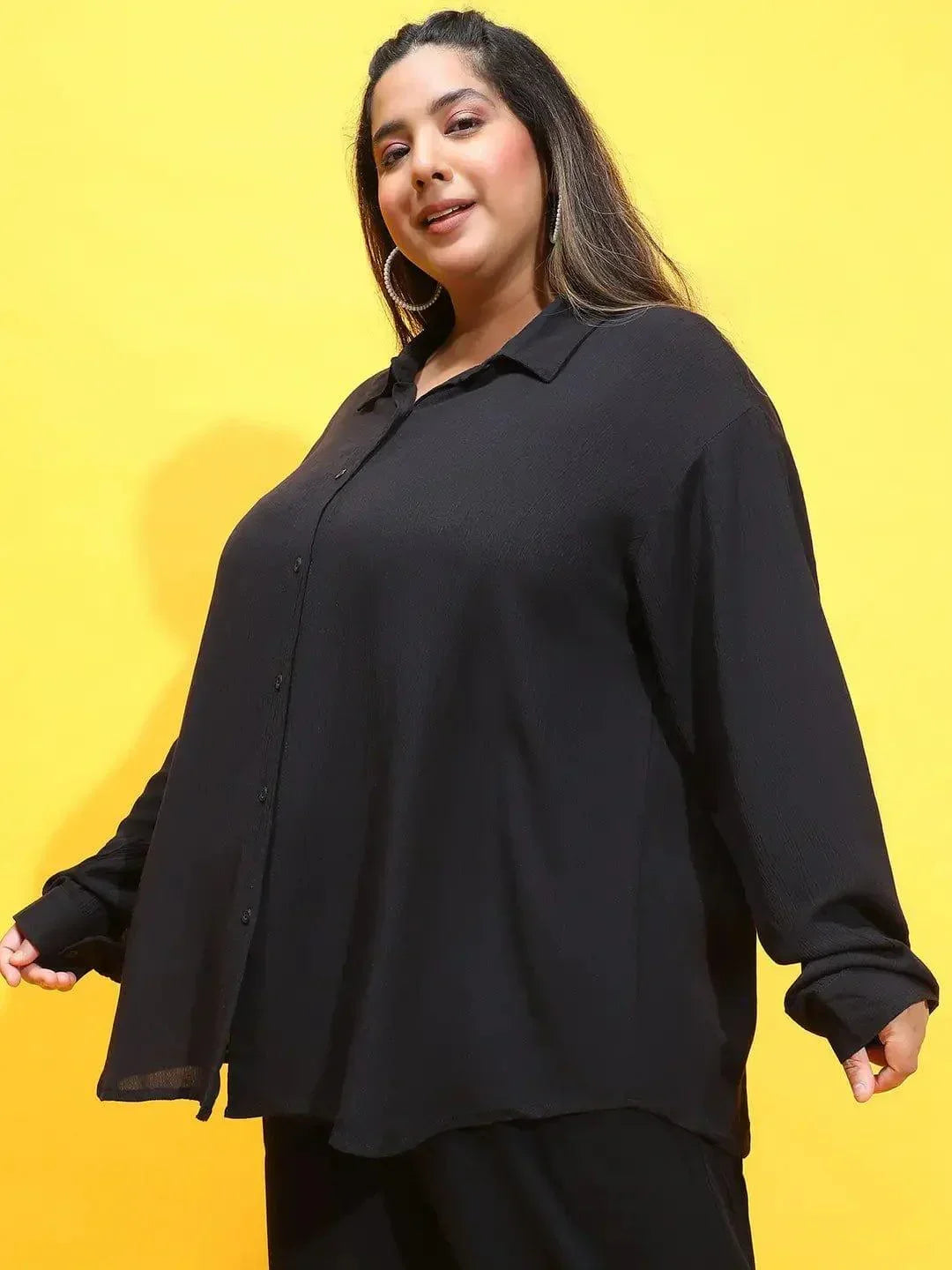 A woman wearing a black shirt and standing against a white background.