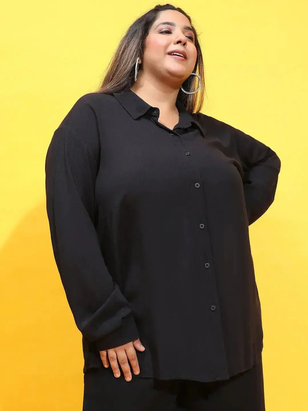 A woman wearing a black shirt and standing against a white background.