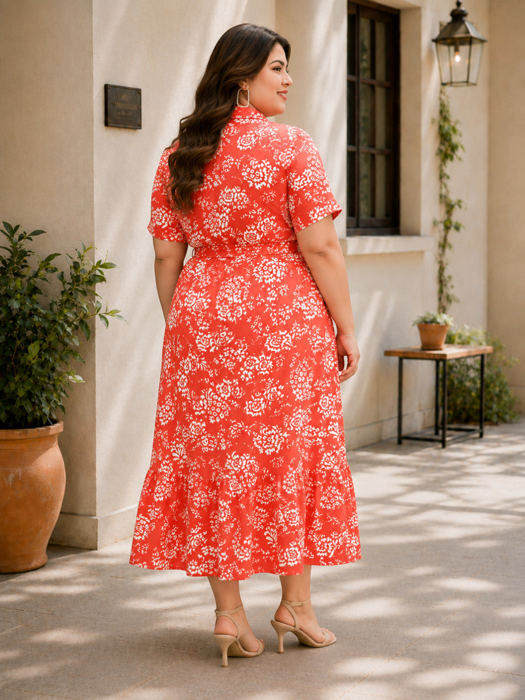 Plus size woman in red floral midi dress with short sleeves, standing outdoors