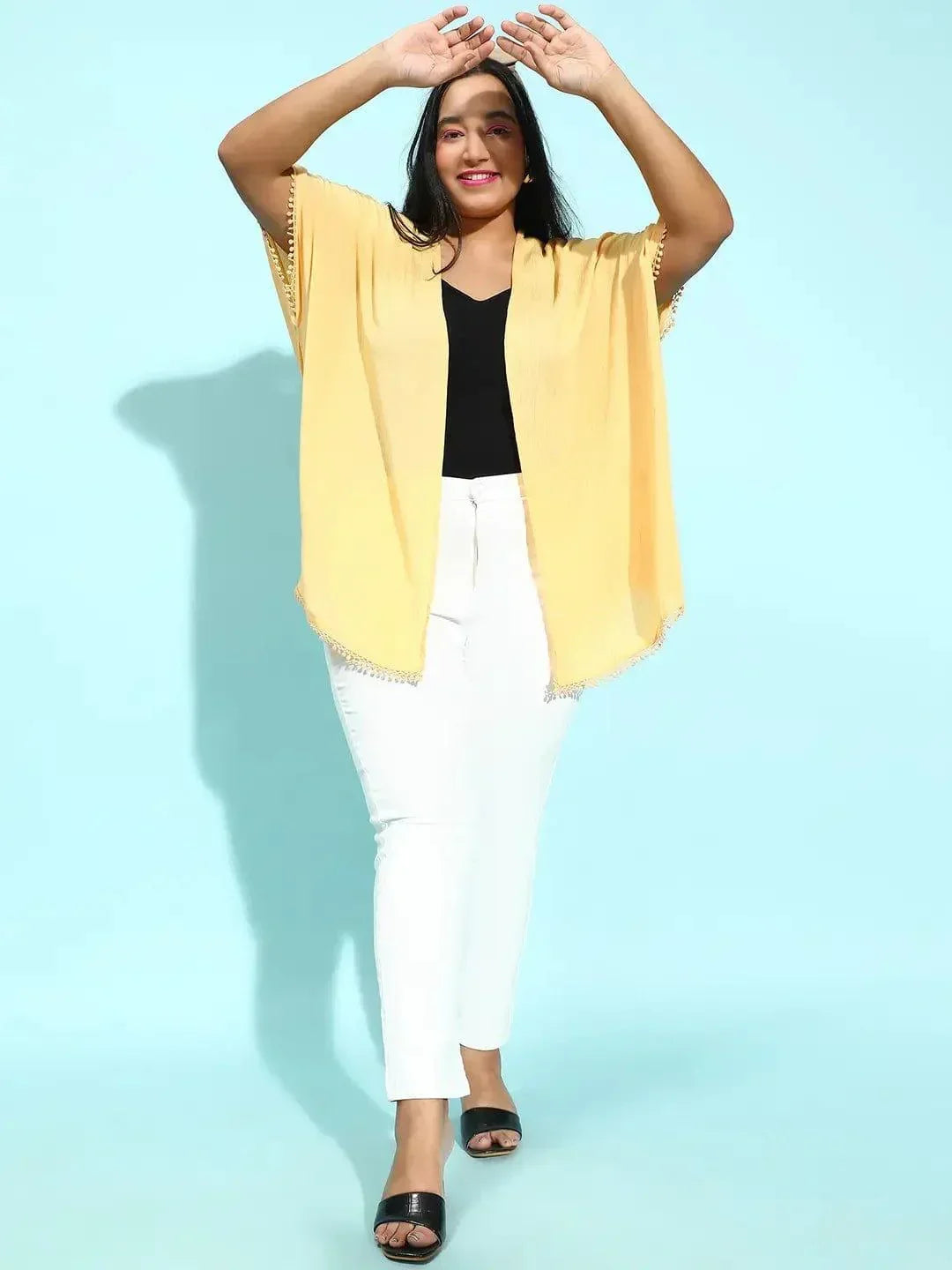 A woman with long dark hair wearing a yellow cardigan and a black top, smiling at the camera.