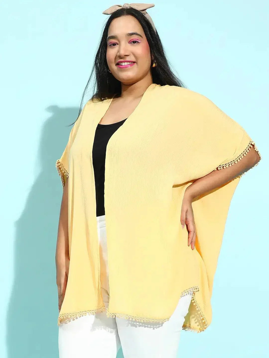 A woman with long dark hair wearing a yellow cardigan and a black top, smiling at the camera.