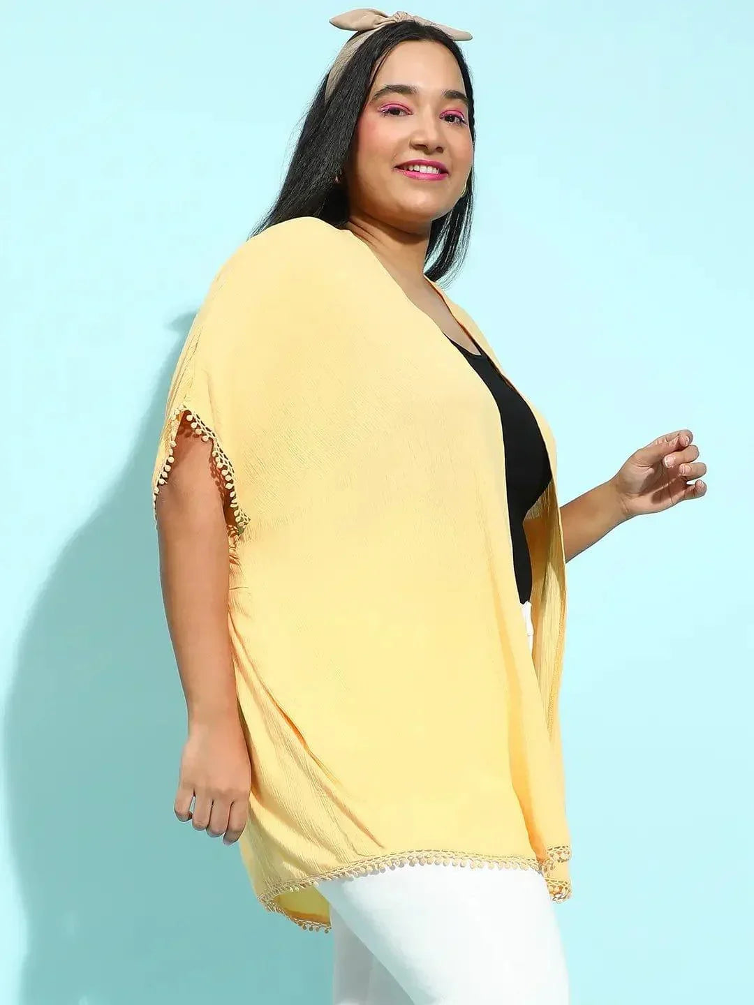 A woman with long dark hair wearing a yellow cardigan and a black top, smiling at the camera.