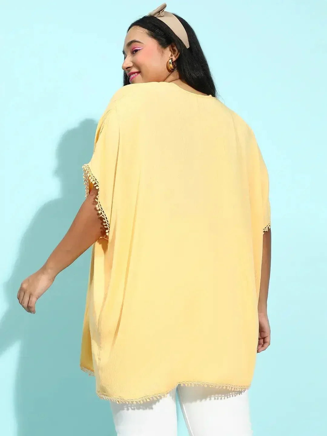 A woman with long dark hair wearing a yellow cardigan and a black top, smiling at the camera.