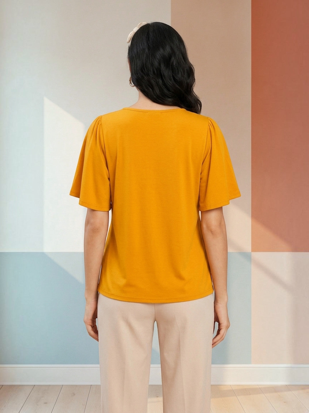 Mustard yellow women's blouse with puff sleeves, back view, paired with beige pants for casual fashion