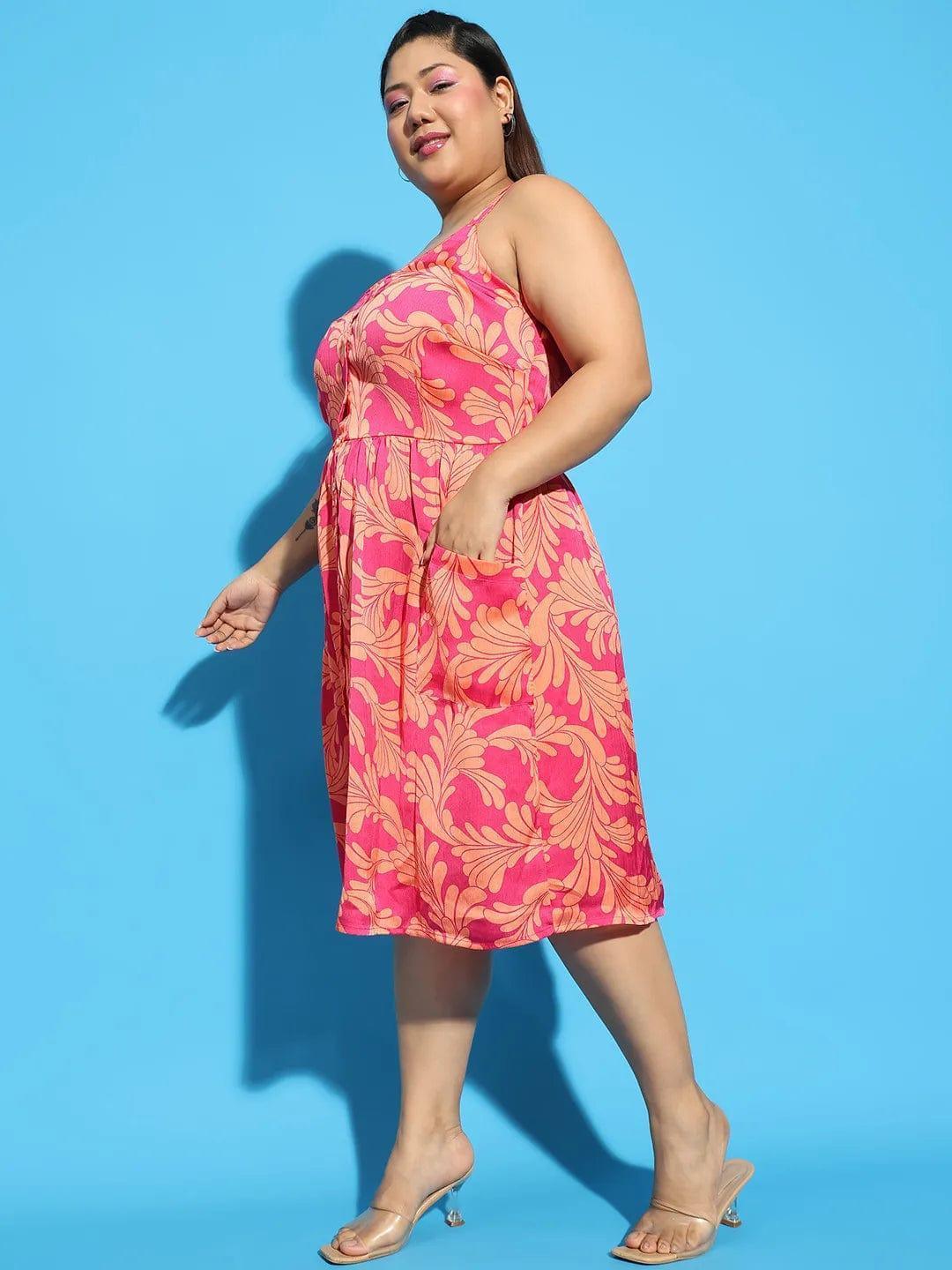 A woman wearing a pink floral print dress and holding a white purse stands against a white background.