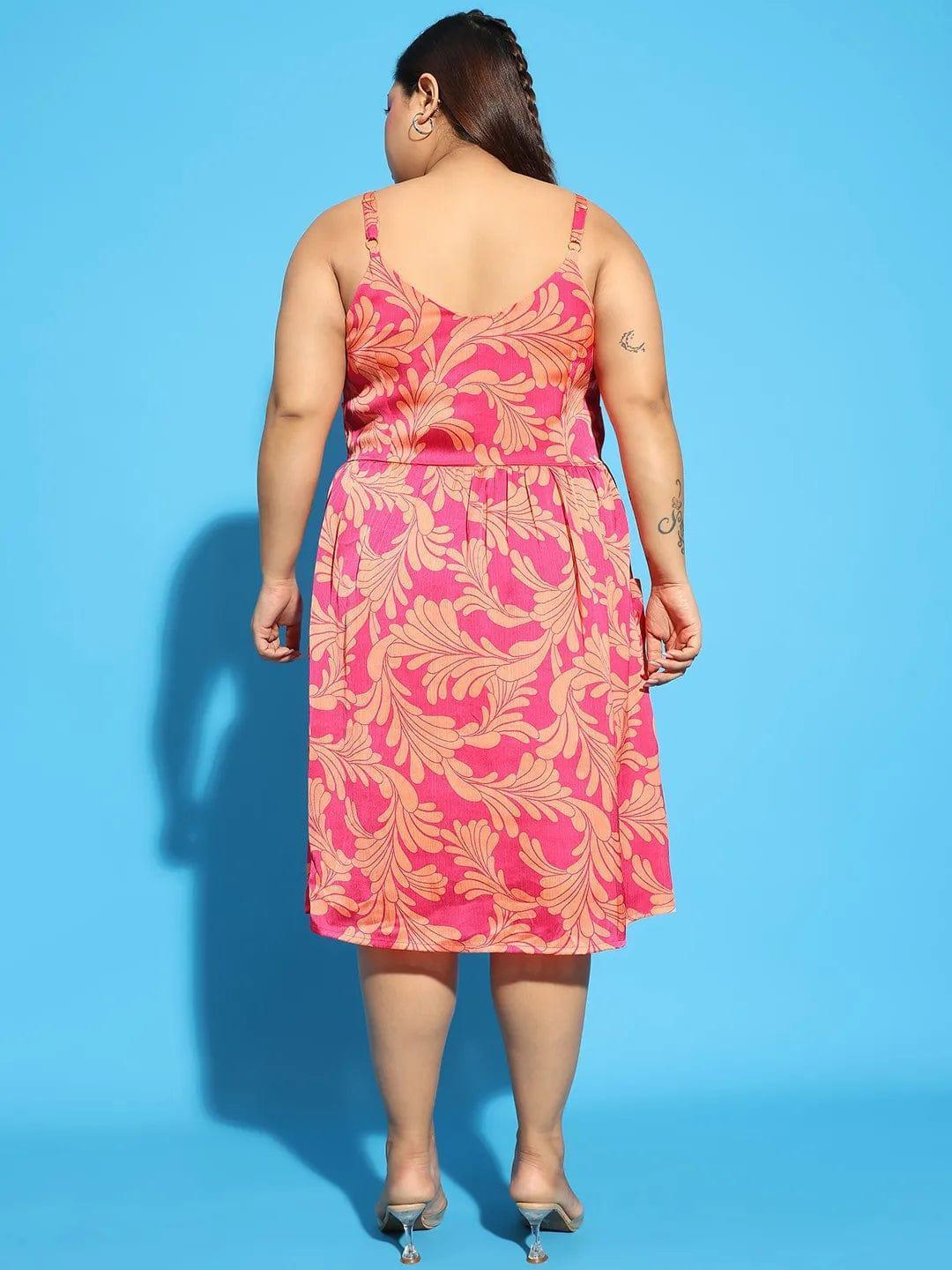 A woman wearing a pink floral print dress and holding a white purse stands against a white background.