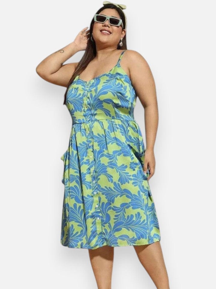 A woman wearing a blue and green floral print dress and sunglasses, smiling and posing for the camera.