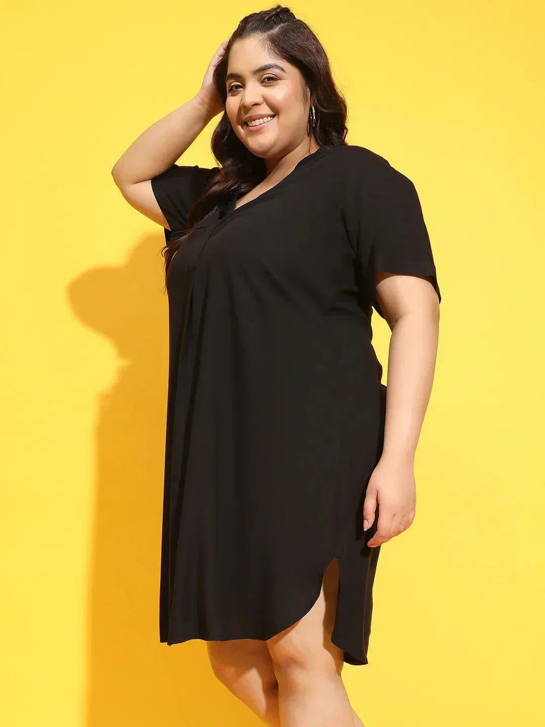 A woman wearing a black dress with a high neckline and short sleeves, smiling and posing for the camera.
