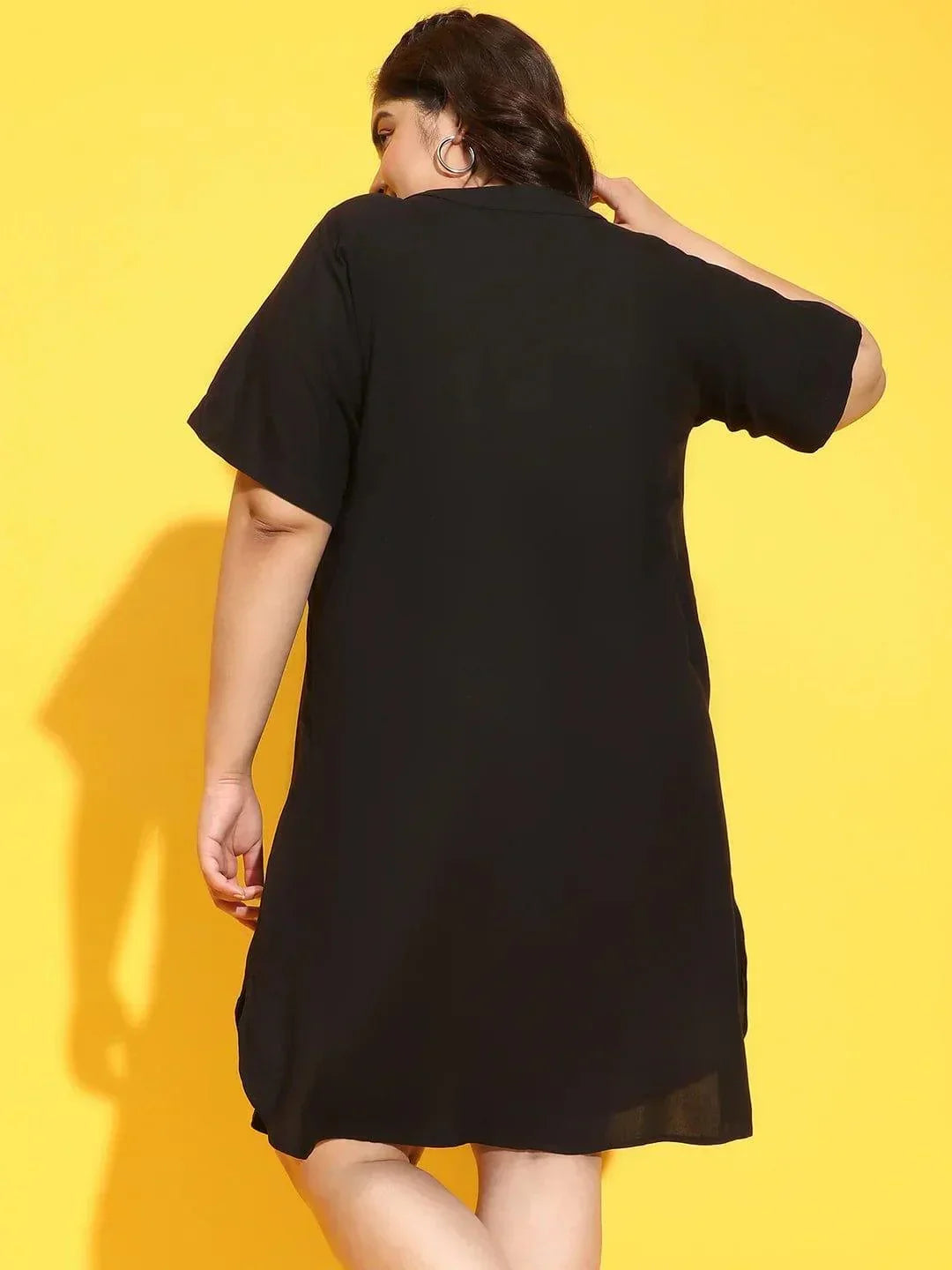 A woman wearing a black dress with a high neckline and short sleeves, smiling and posing for the camera.