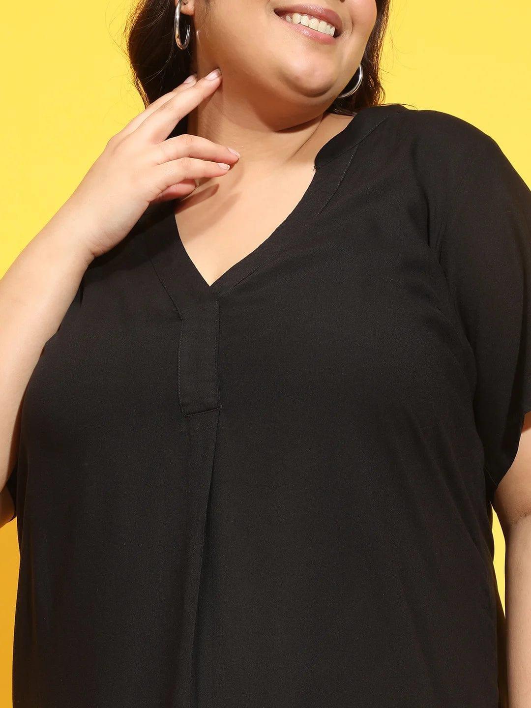 A woman wearing a black dress with a high neckline and short sleeves, smiling and posing for the camera.