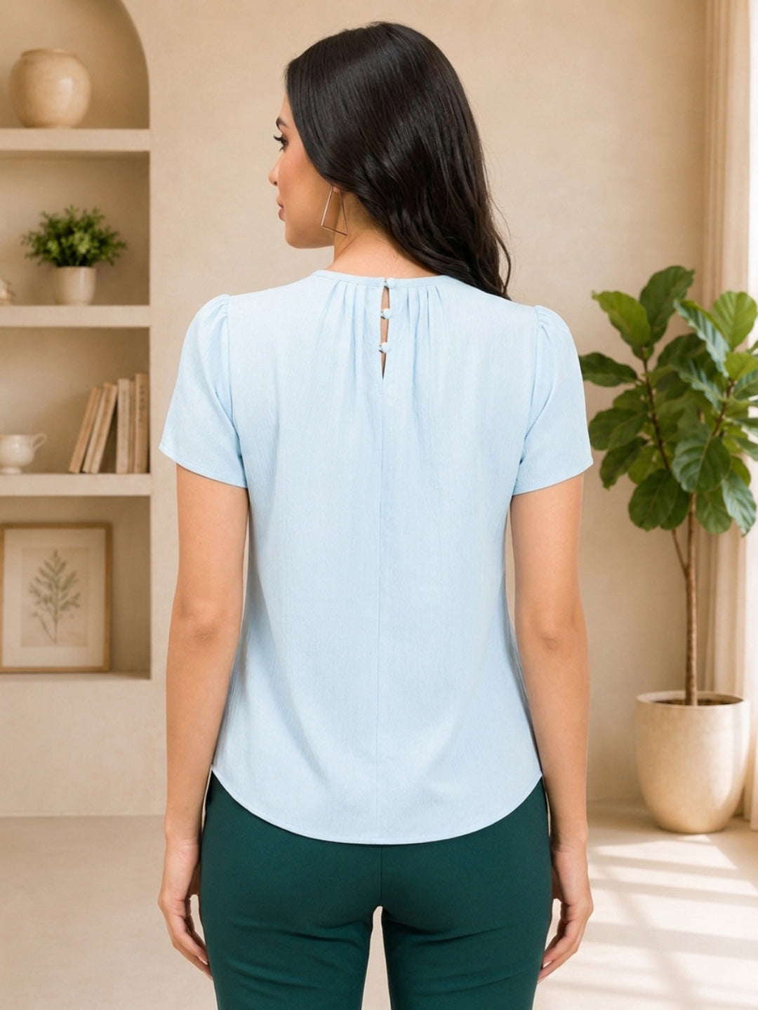 Light blue women's blouse with back button detail, puff sleeves, paired with green pants for casual fashion