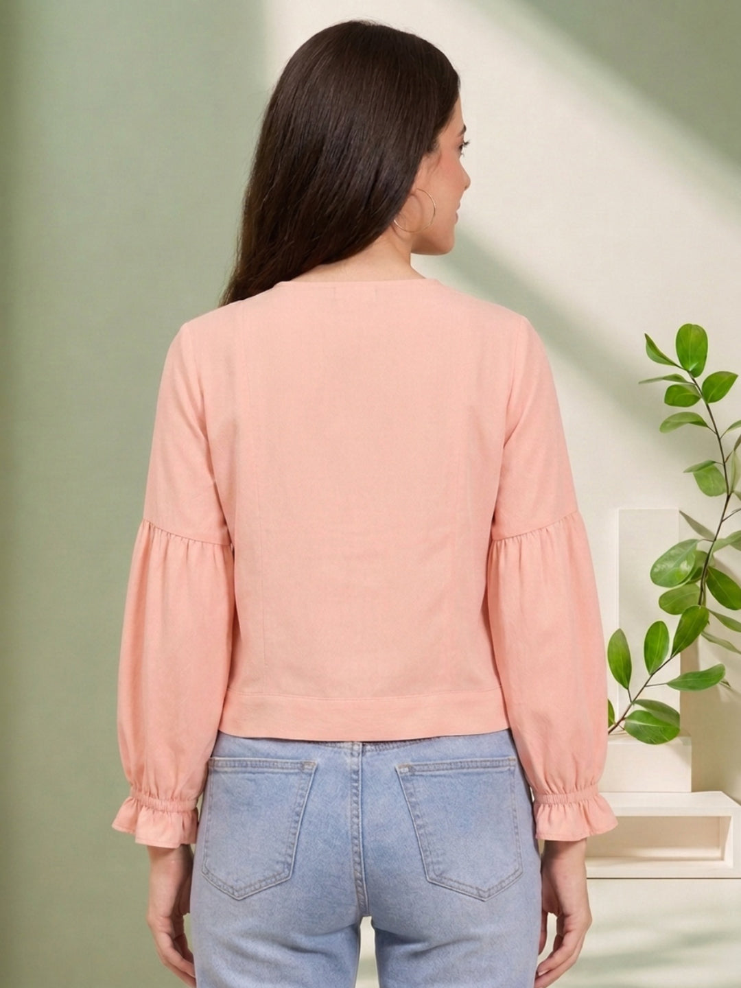 Pink long sleeve top with ruffled cuffs, paired with light wash jeans, back view