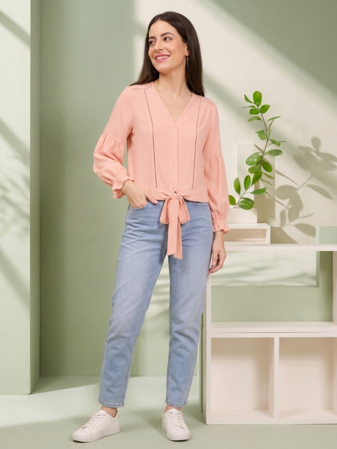 Pink tie-front blouse with ruffled sleeves paired with light blue jeans and white sneakers