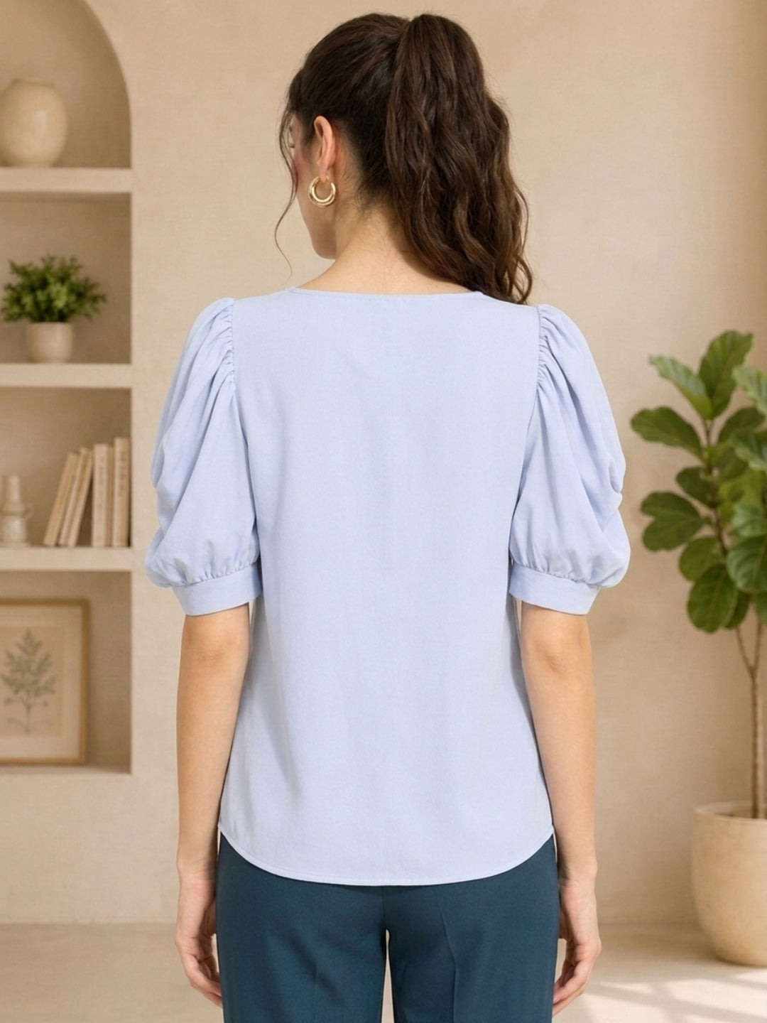 Light blue women's blouse with puff sleeves, back view, paired with dark pants for casual fashion