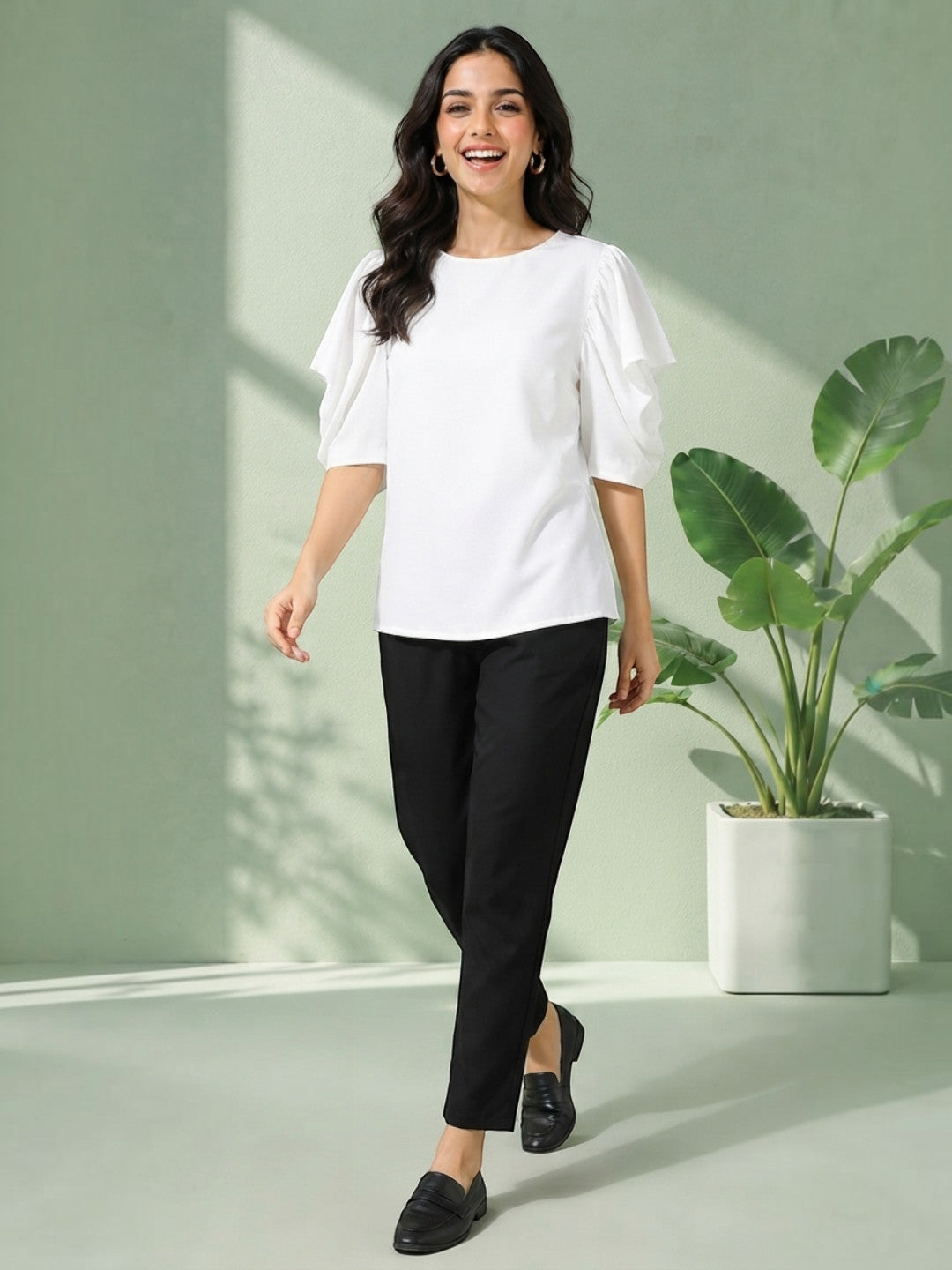 Woman in white ruffle sleeve top and black pants, stylish plus size outfit for casual wear