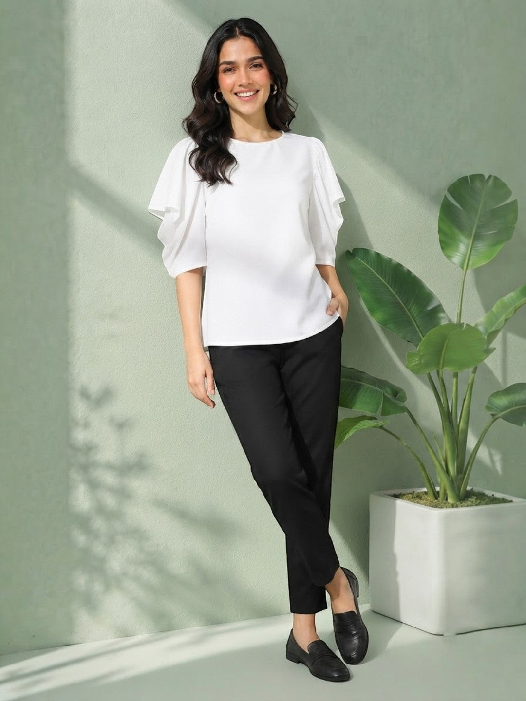 Woman in white ruffle sleeve top and black pants, stylish plus size outfit for casual wear