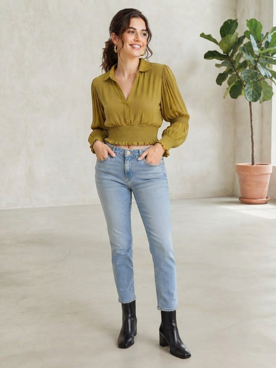 Woman in olive green ruffled blouse, light wash jeans, and black ankle boots, plus size fashion
