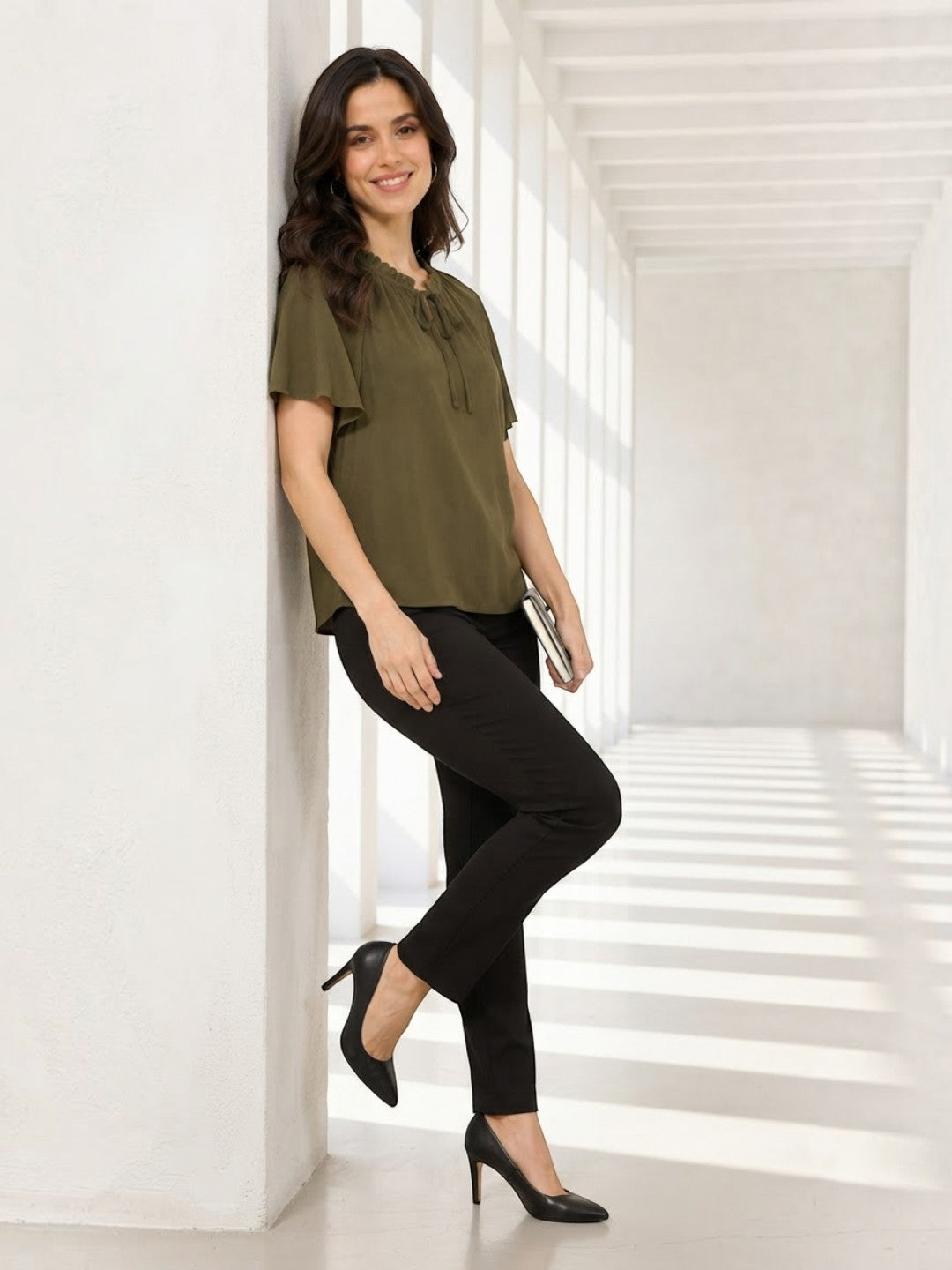 Woman in olive green ruffle top and black pants, stylish plus size outfit for work or casual wear
