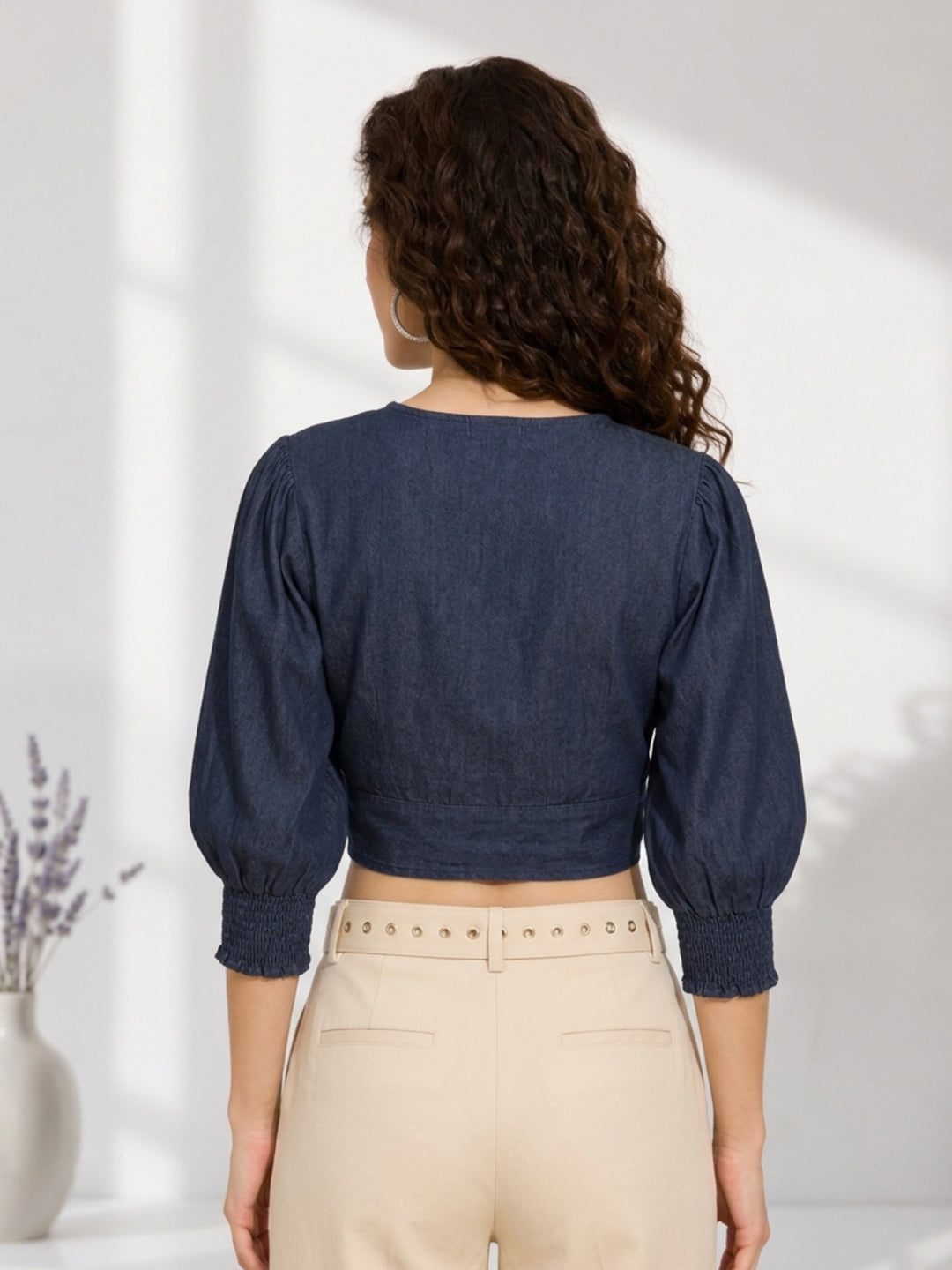 Woman wearing navy blue cropped denim top with puff sleeves, paired with beige high-waist pants