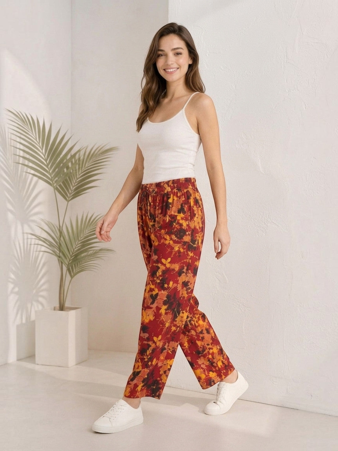 Woman in floral print wide-leg pants with white tank top and sneakers, plus size fashion