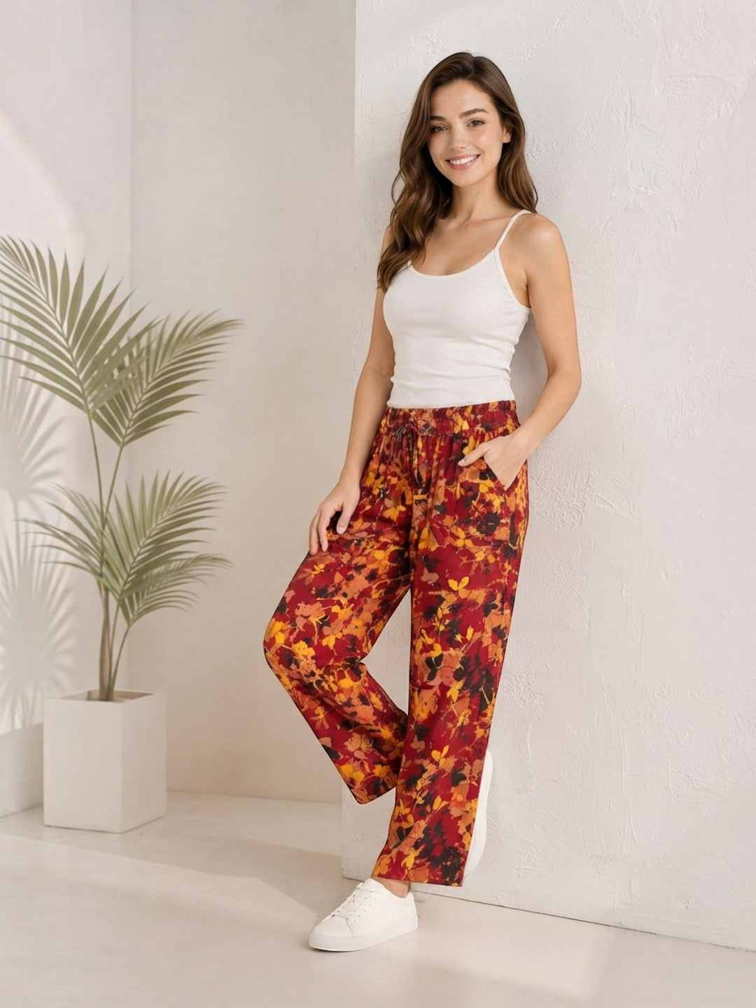 Woman in floral print wide-leg pants with white tank top and sneakers, casual plus size fashion