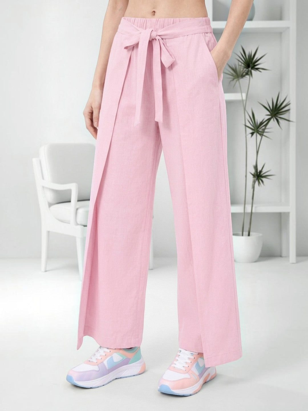Pink wide-leg tie-waist pants with side slits, styled with pastel sneakers for casual women's fashion.