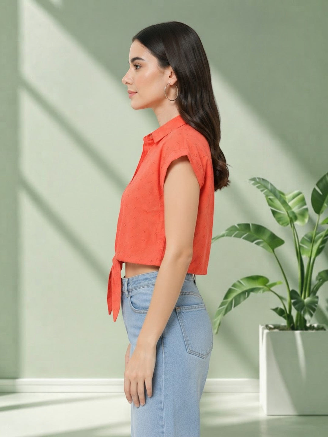 Woman in coral crop top with tie front, paired with light blue jeans, stylish plus size fashion