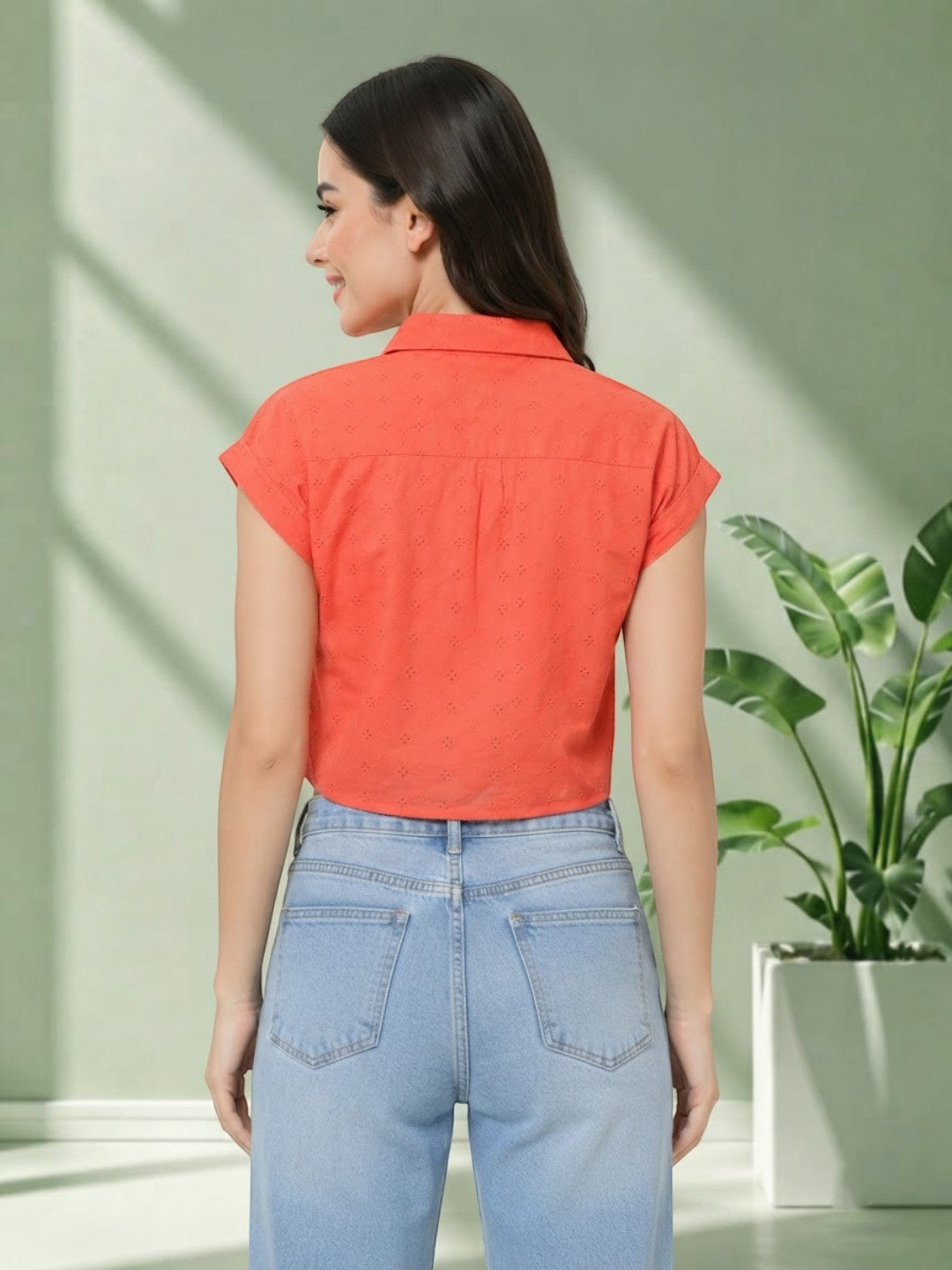 Woman wearing coral eyelet short sleeve shirt with light blue jeans, back view