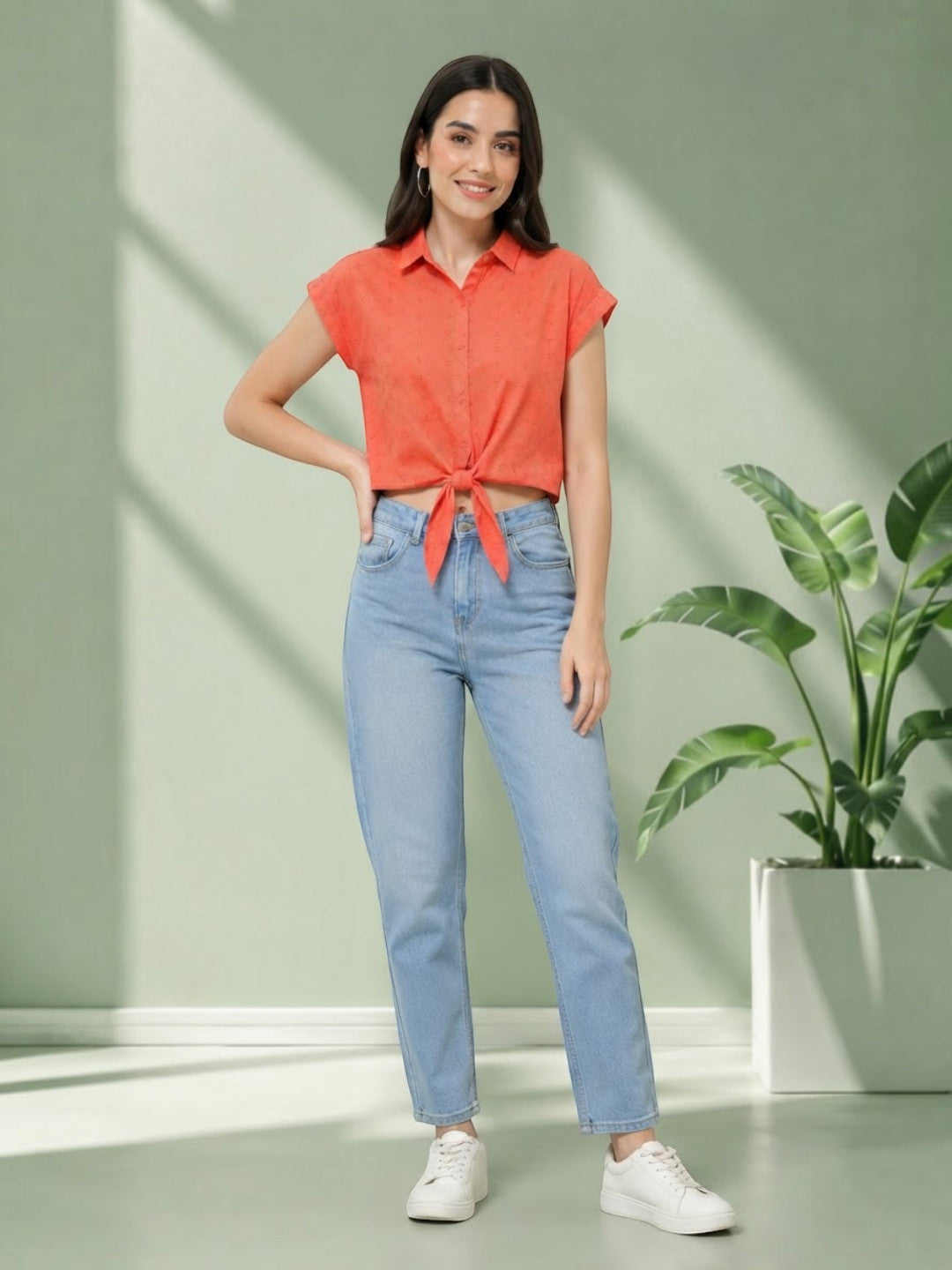 Woman in coral tie-front crop top and light wash jeans, stylish plus size fashion outfit