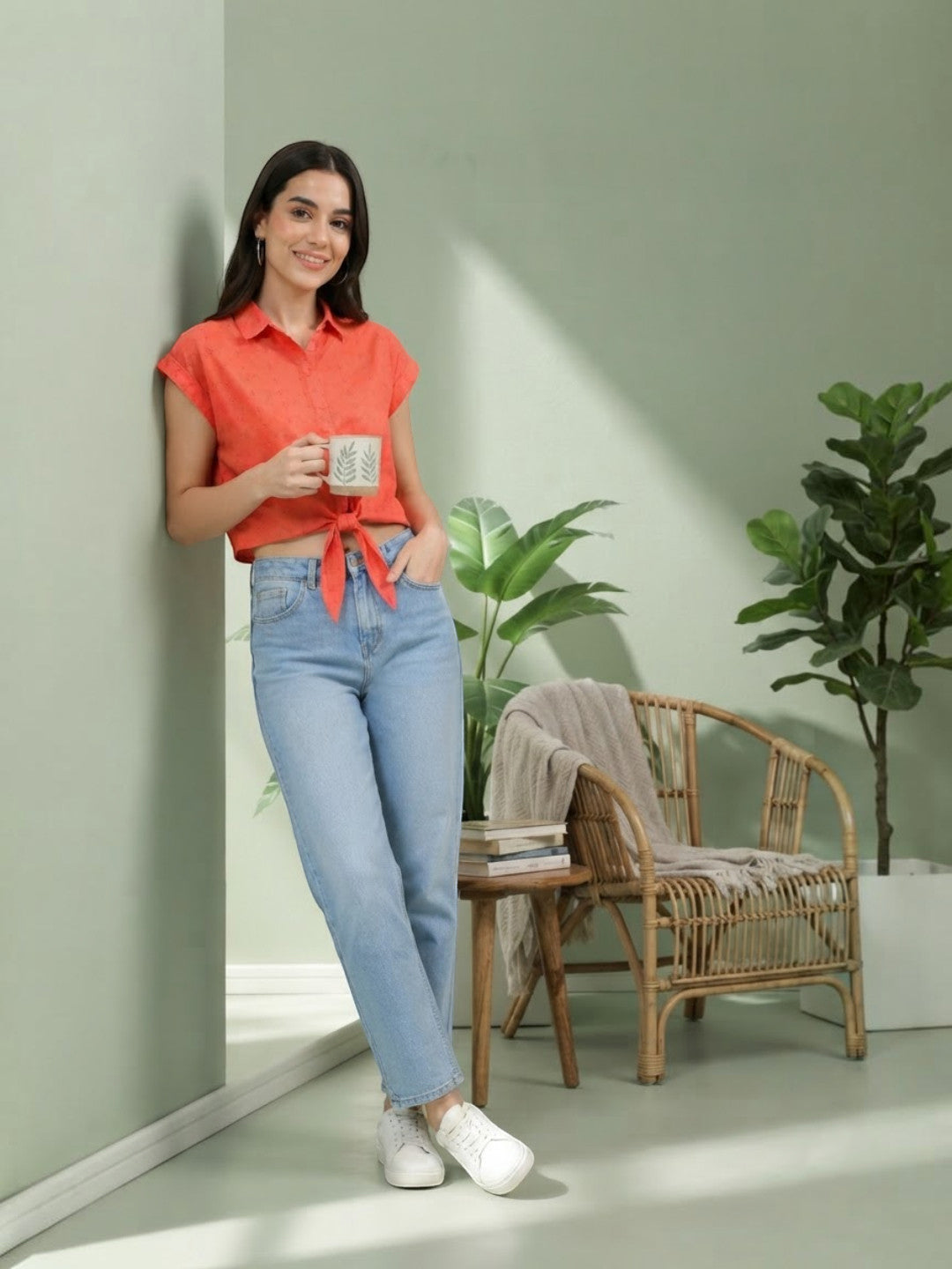 Woman in orange tie-front shirt and light blue jeans, holding mug, casual plus size fashion