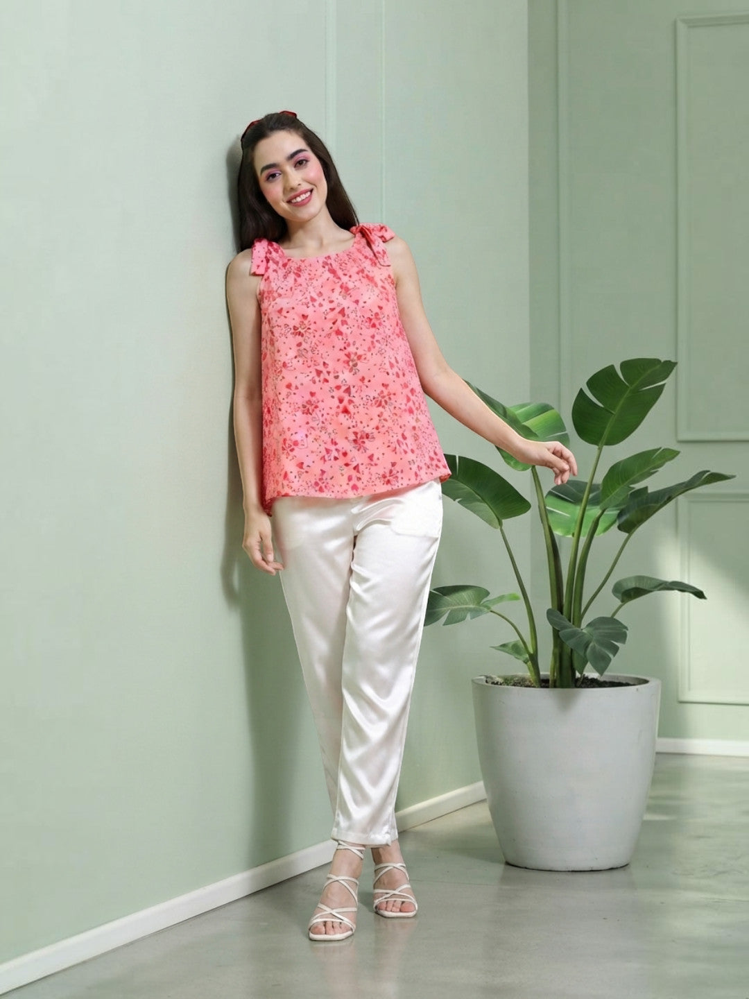 Pink floral sleeveless top with bow straps, paired with white satin pants, perfect for trendy women's fashion.