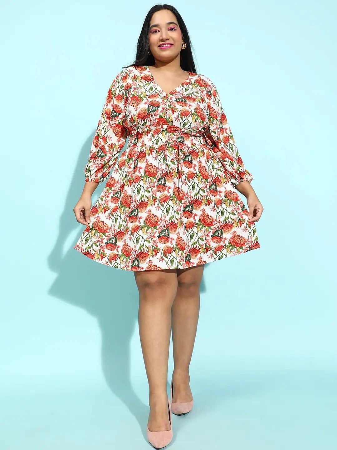 A woman wearing a white dress with a floral print, smiling at the camera.