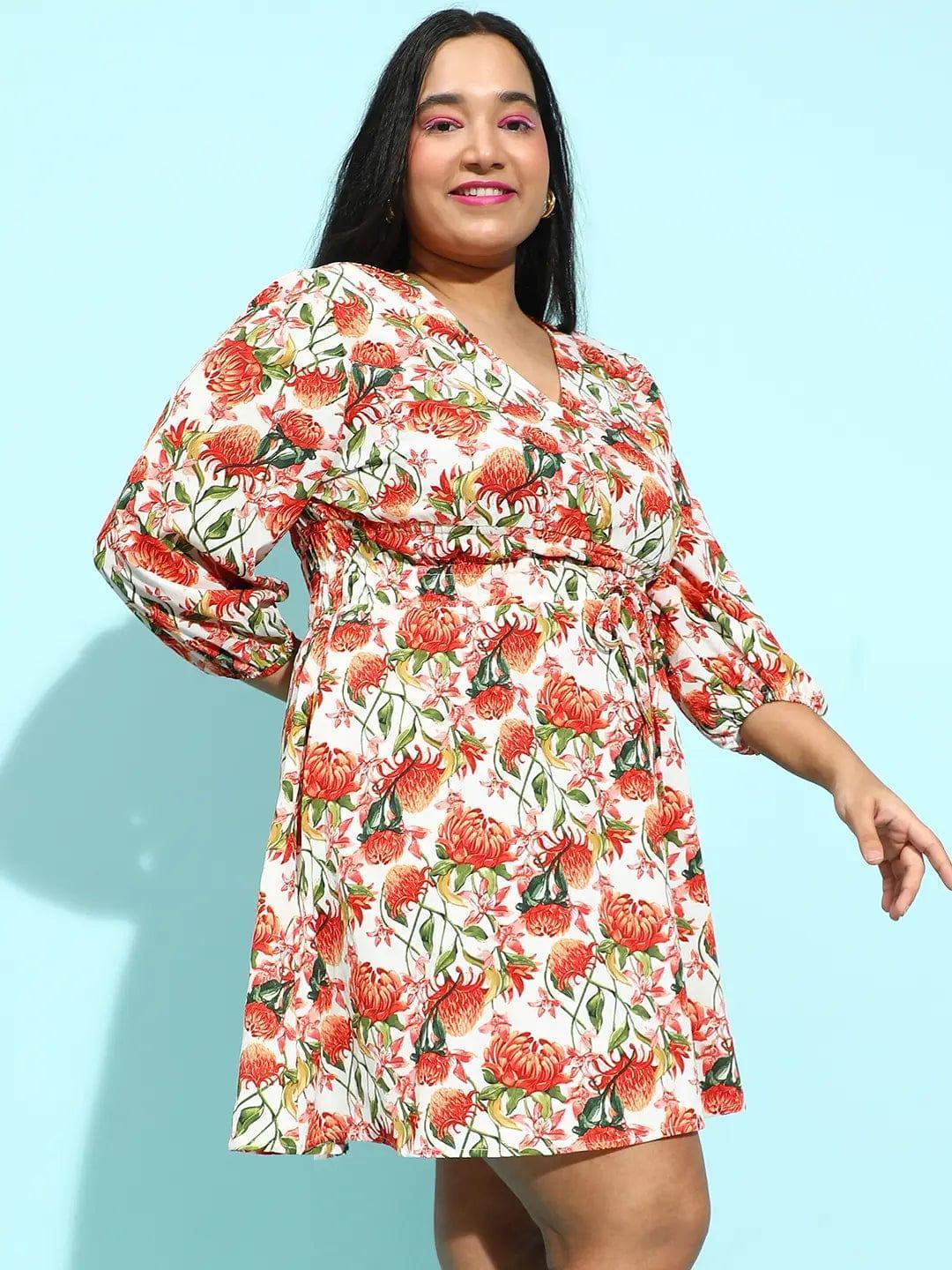 A woman wearing a white dress with a floral print, smiling at the camera.
