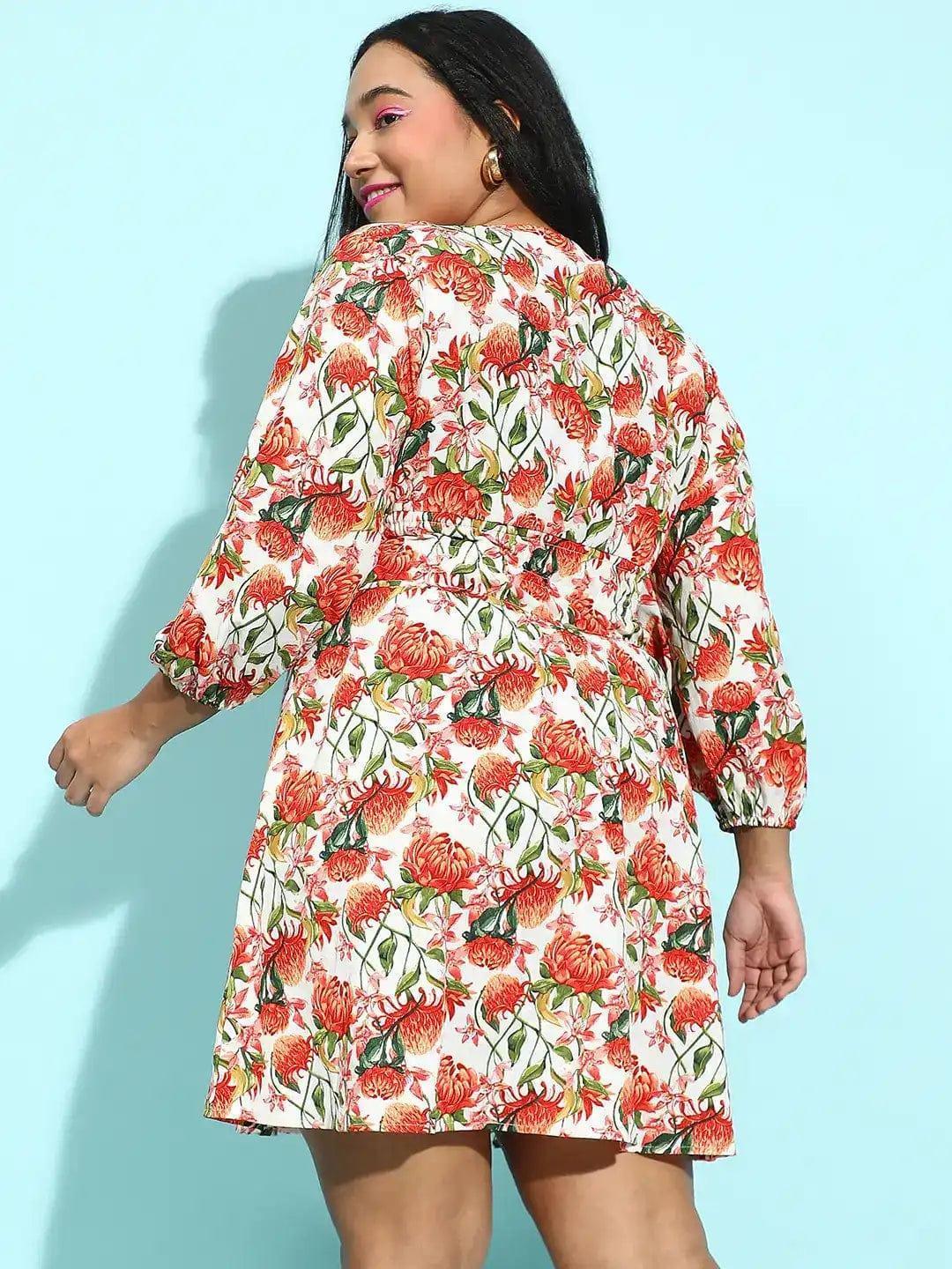 A woman wearing a white dress with a floral print, smiling at the camera.