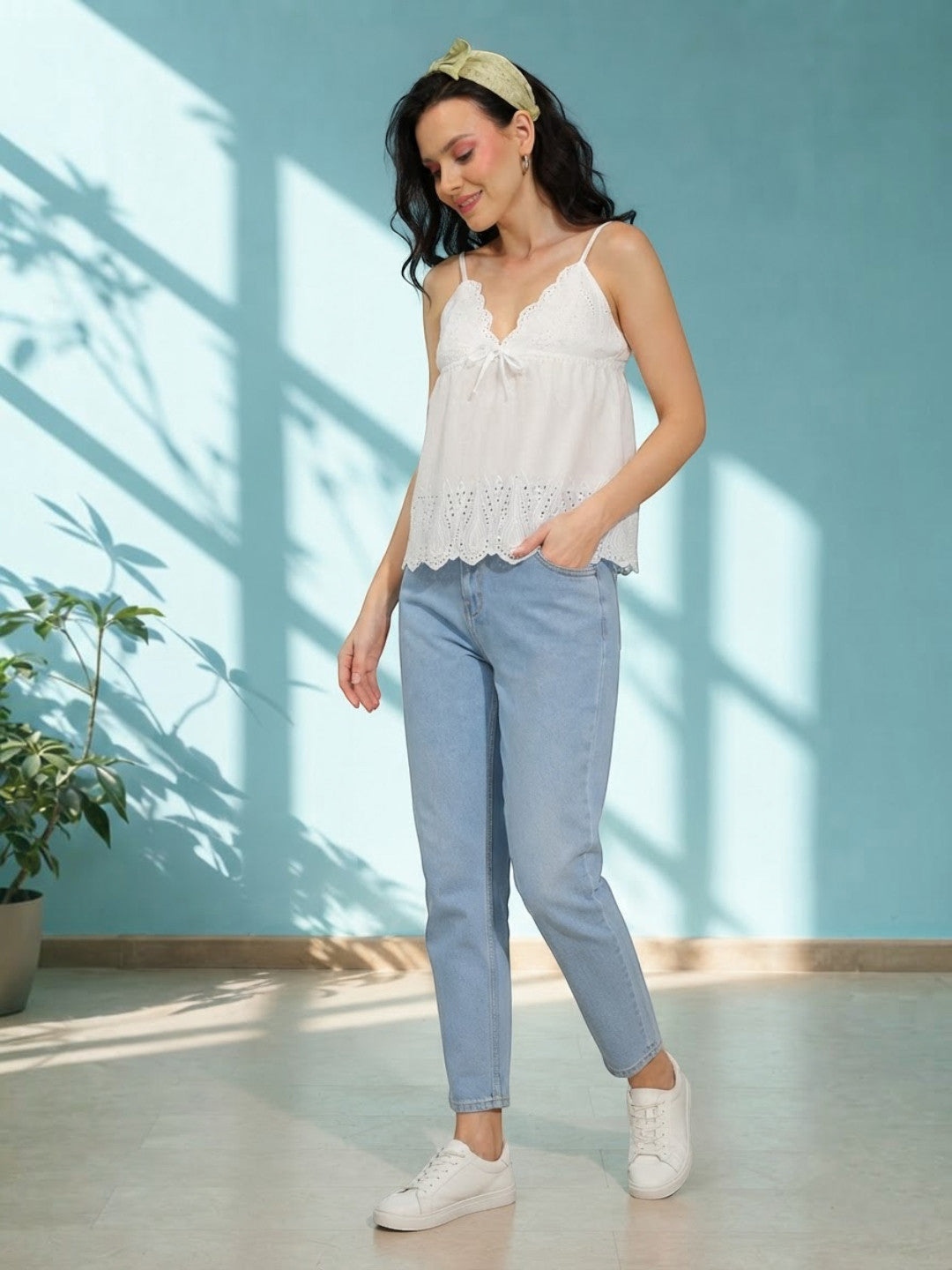 Woman in white lace camisole top and light blue jeans, casual summer outfit with white sneakers