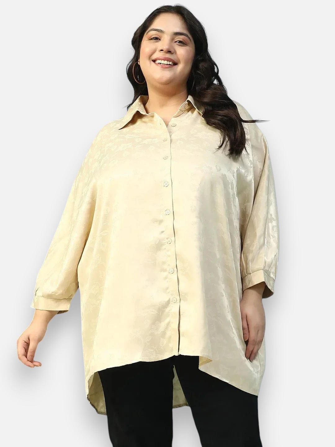 A smiling woman wearing a cream-colored shirt with a button-down front and long sleeves.