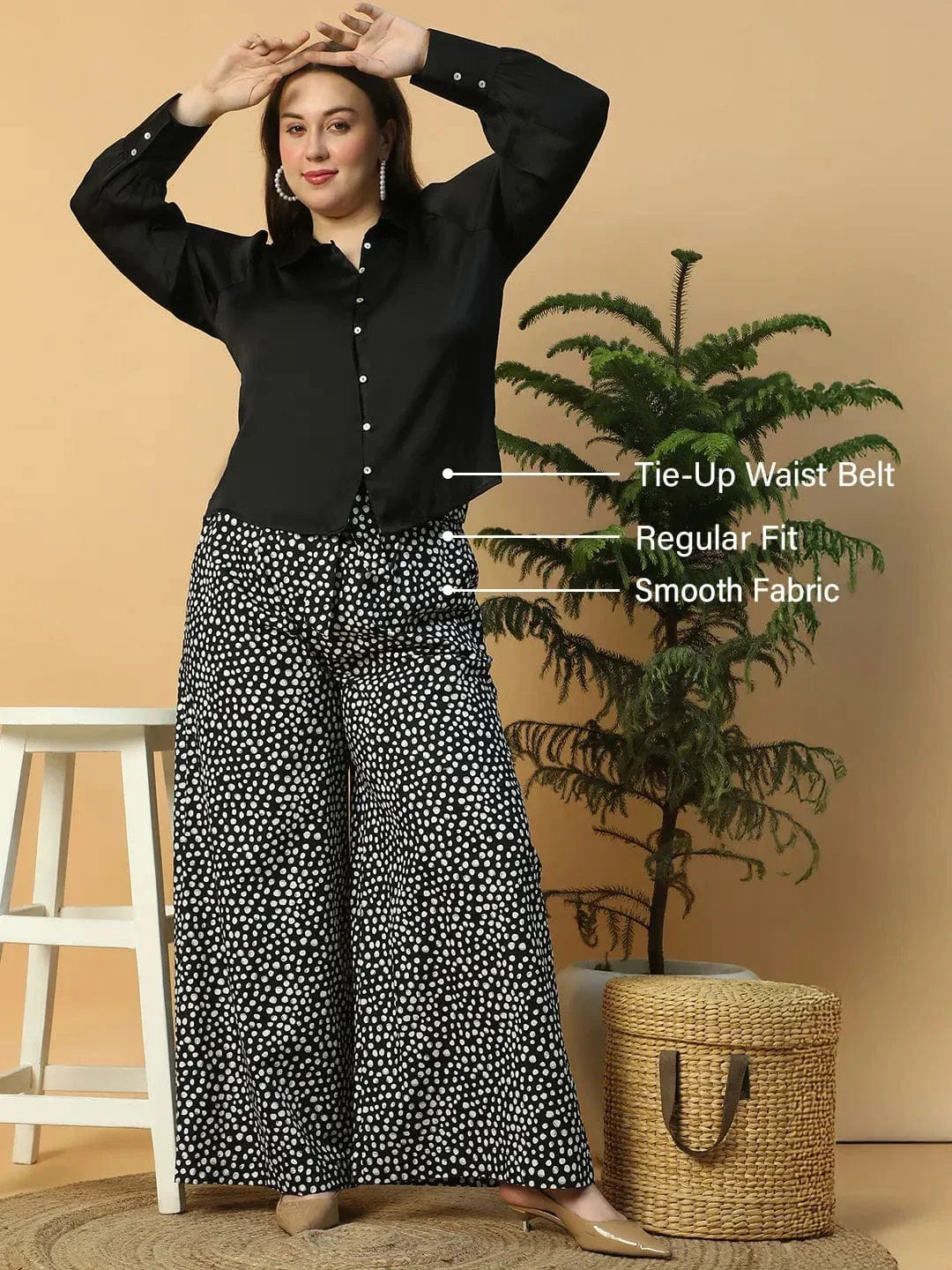 A person wearing wide-leg pants with a black and white polka dot pattern.