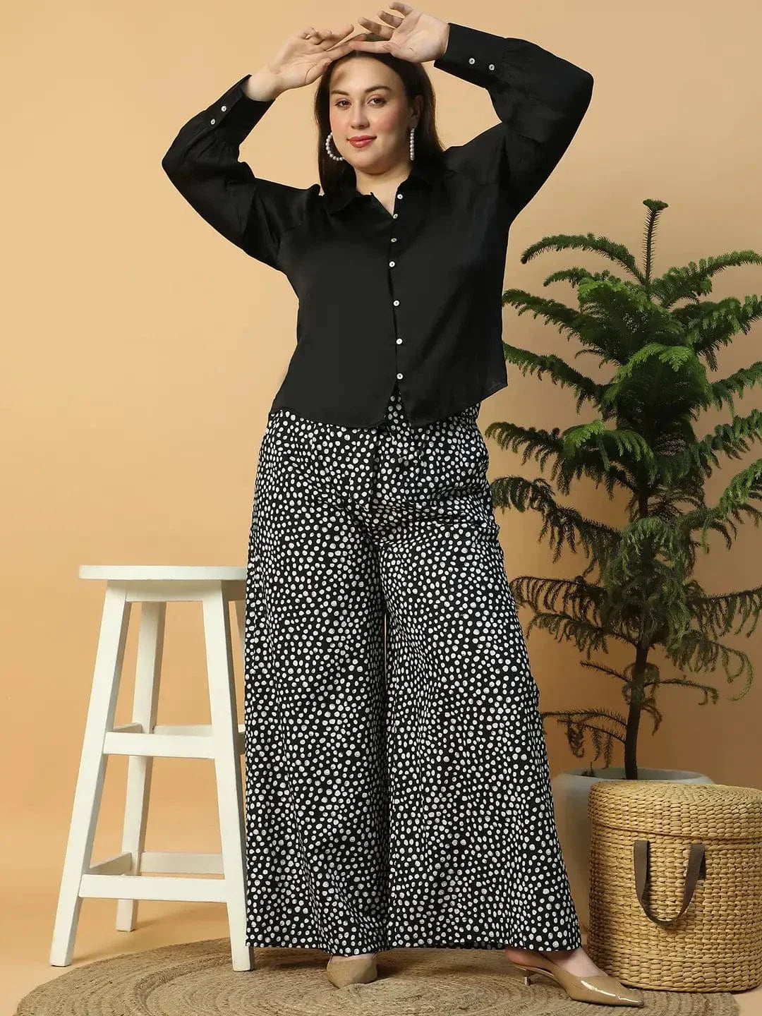 A person wearing wide-leg pants with a black and white polka dot pattern.