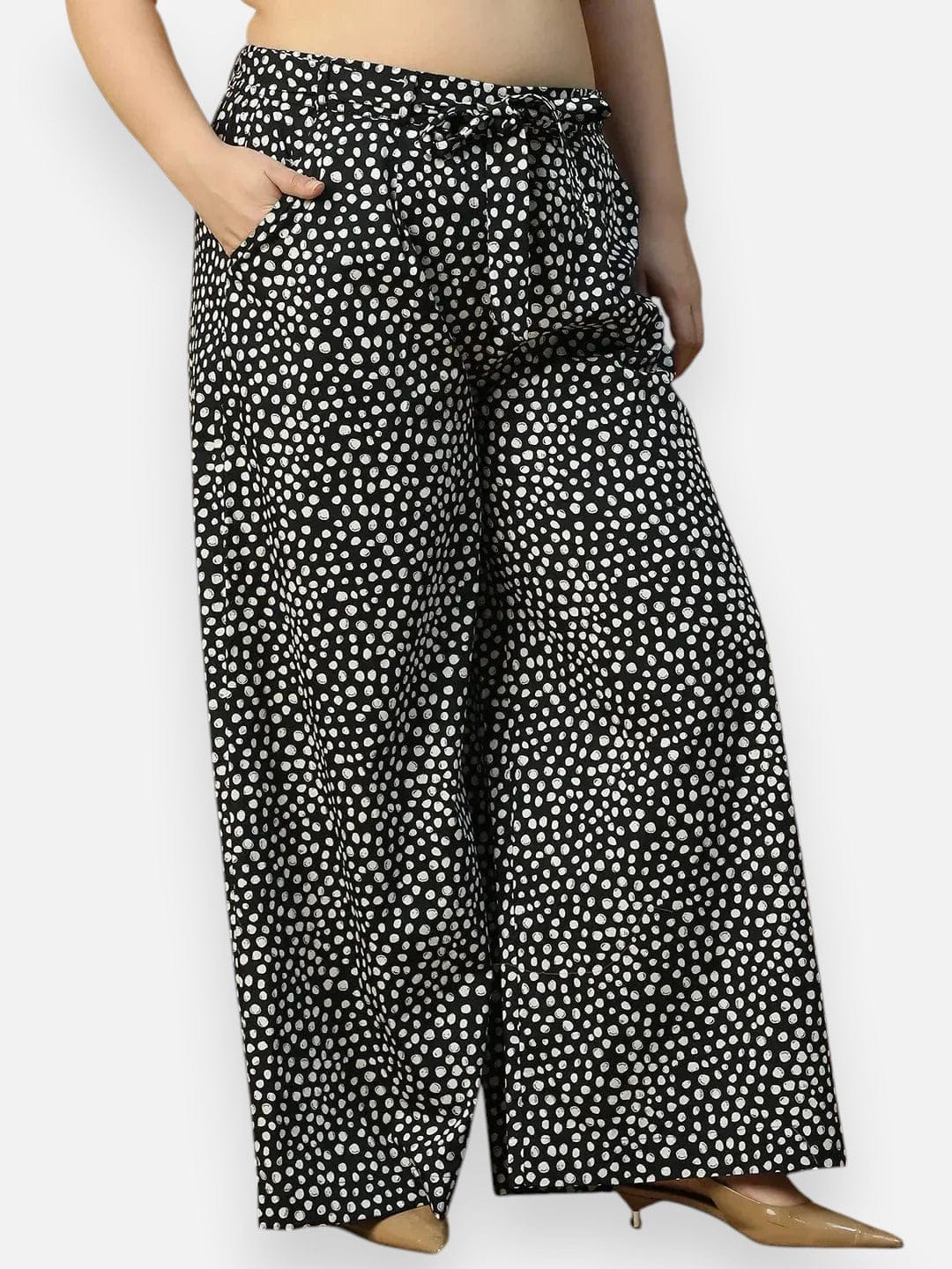 A person wearing wide-leg pants with a black and white polka dot pattern.