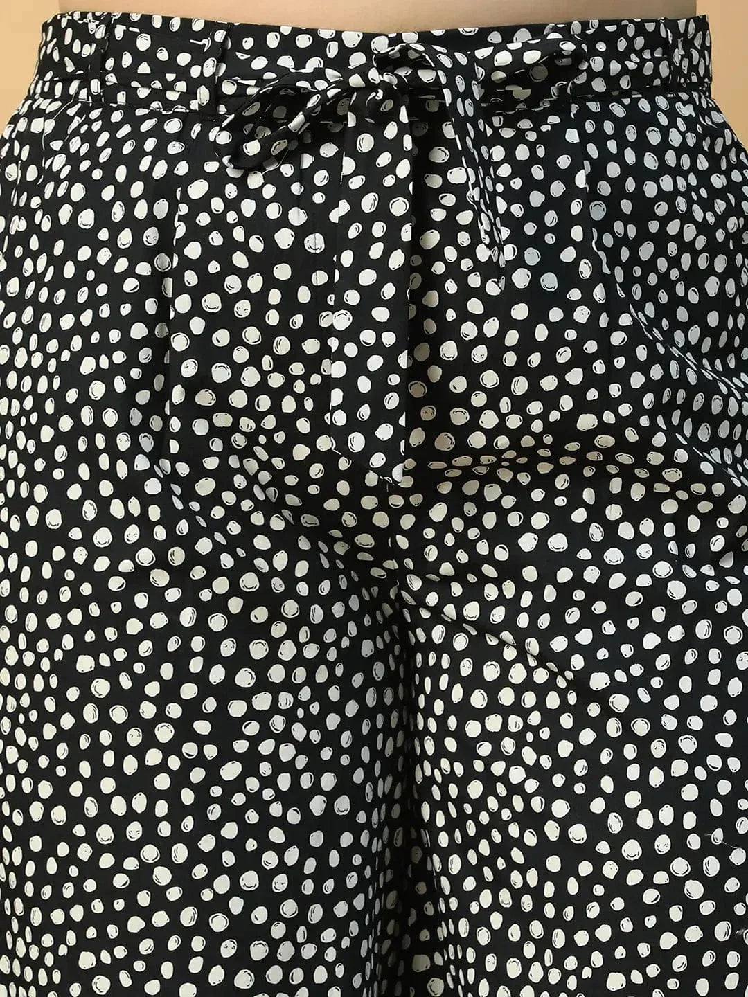 A person wearing wide-leg pants with a black and white polka dot pattern.